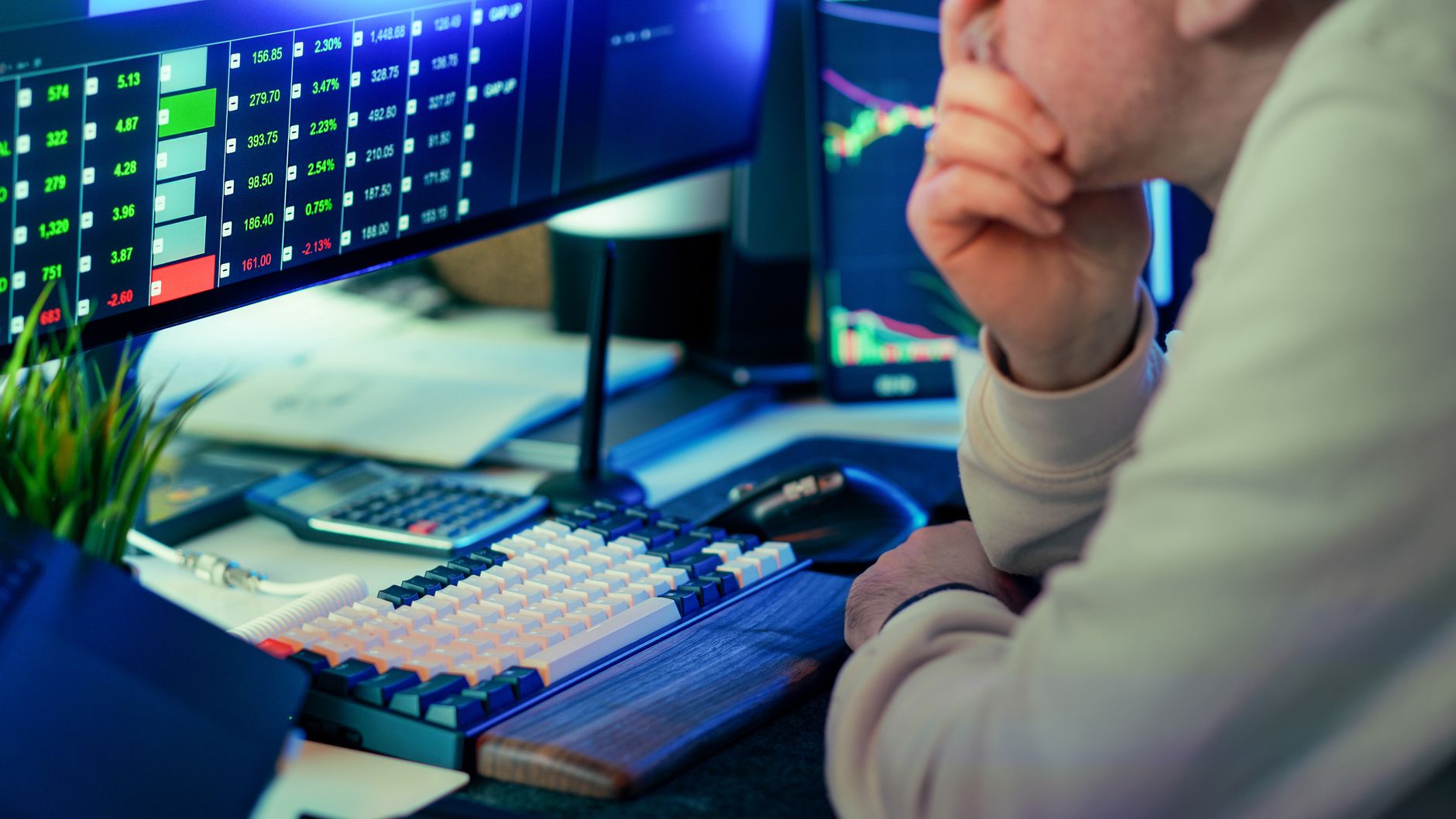 Trader observa atentamente dados financeiros em vários monitores